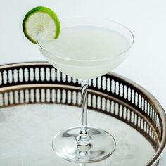 a margarita sitting on top of a metal tray with a lime wedge in the rim