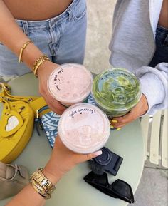 three people holding cups with drinks in them on top of a table next to each other