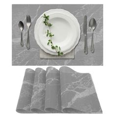 a place setting with silverware, napkins and plates on a gray table cloth