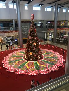 a large christmas tree in the middle of an indoor shopping mall with lights on it