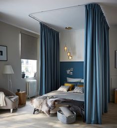 a bed room with a neatly made bed and blue drapes hanging from the ceiling