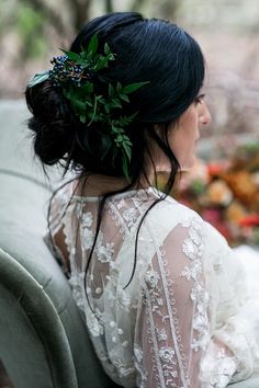 a woman sitting on top of a couch wearing a flower in her hair and looking off to the side