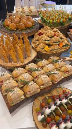 a table topped with lots of different types of sandwiches and pastries on wooden trays