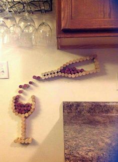 two wine glasses are hanging on the wall next to some corks that have been arranged in the shape of a man's head