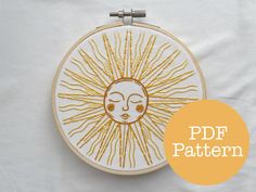 an embroidery pattern with the sun on it's face in gold and white thread