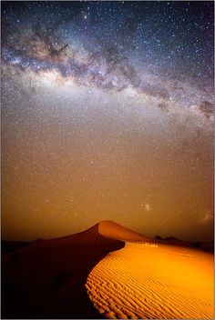 the night sky is filled with stars above sand dunes