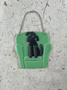 a green and black dog sitting on top of a green chair with chains hanging from it's sides