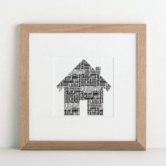 a wooden frame holding a black and white print with the words home on it in different languages