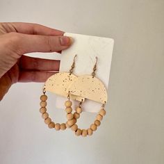 a pair of earrings with wooden beads hanging from it's earring hooks on a piece of paper