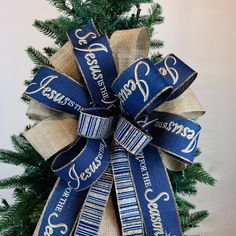 a blue and white christmas tree bow with the words jesus loves us all on it