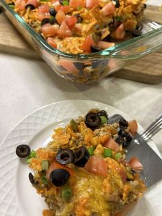 a casserole dish with black olives, tomatoes and other toppings on it