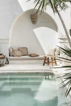 a pool with a bench next to it and a potted plant in the corner