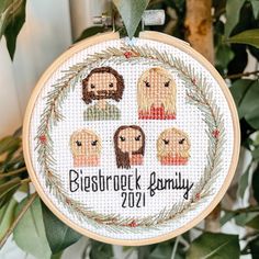 a cross stitch ornament hanging on a tree branch with the words, bibsburg family