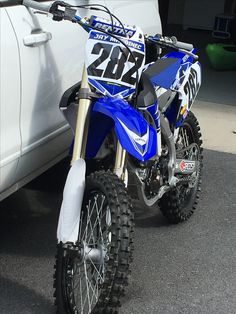 a blue dirt bike parked next to a white truck