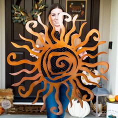 a woman is standing in front of a door holding a paper cut out of a sun