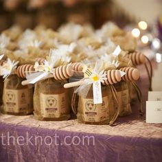 small jars filled with honey sitting on top of a table covered in bees and flowers