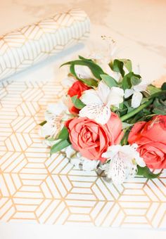 a bouquet of flowers sitting on top of a table next to a folded piece of paper