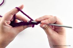 two hands crocheting the ends of a purple piece of yarn with a needle