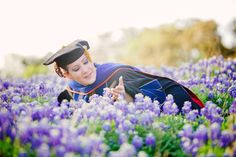 a woman laying in the middle of a field of purple flowers wearing a hat and gown