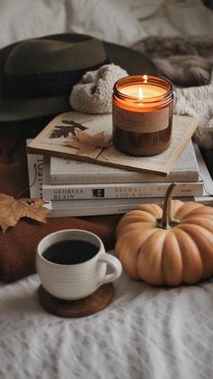 a stack of books and a candle on top of each other next to a cup of coffee