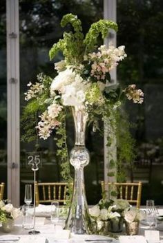 a tall glass vase filled with flowers on top of a table