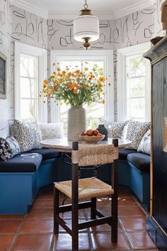 a room with blue couches and orange flowers in a vase on top of a table