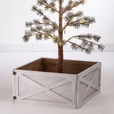 a small tree in a wooden box with lights on the top and bottom part of it