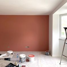 an empty room with some paint on the walls and two ladders in front of it