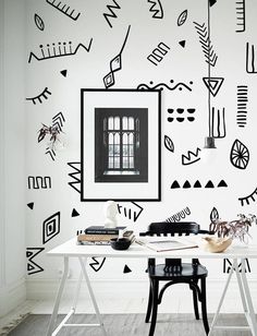 a white table sitting in front of a wall with black and white designs on it