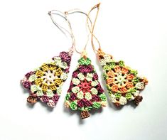 three crocheted ornaments hanging from strings on a white surface, one is multicolored and the other has an ornament