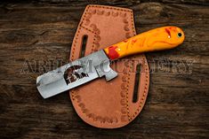 an orange knife sitting on top of a leather case