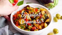 an eggplant caponata in a white bowl surrounded by olives