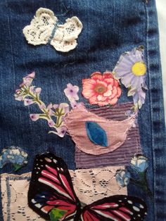 a butterfly sitting on top of a blue jean jacket with flowers and butterflies around it