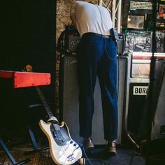 a man standing next to a guitar and amp