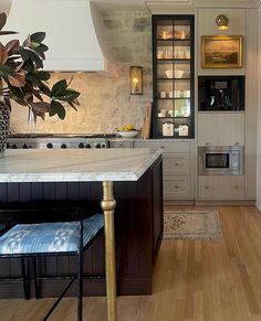 a kitchen with white cabinets and marble counter tops, along with an island in the middle