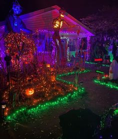 halloween decorations in front of a house with purple and green lights on the yard,