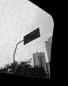 rain drops on the windshield of a car as it drives down a city street with tall buildings in the background