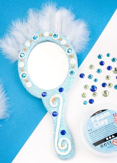 a blue and white mirror next to some feathers on top of a table with confetti