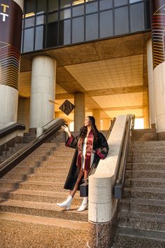 a woman in graduation gown standing on stairs