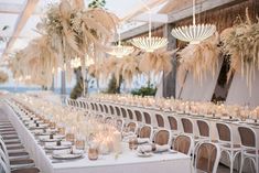 a long table set up with white linens and tall centerpieces