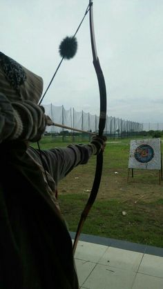 a man holding a bow and arrow in front of an archery target