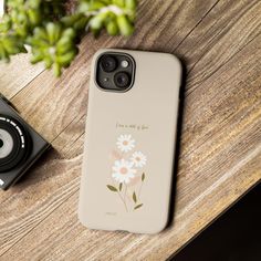 an iphone case sitting on top of a wooden table next to a camera and plant