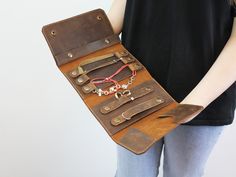 a woman holding a leather case with various items in it's pockets and the contents inside