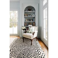 a living room with a chair, bookshelf and rug