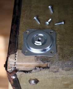 a piece of metal sitting on top of a wooden table next to screws and nails