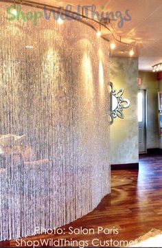 the inside of a salon with wooden floors and white curtains on the wall behind it