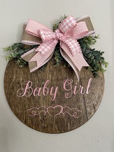 a wooden sign that says baby girl with pink bows and greenery on it's side