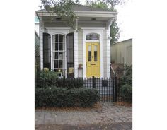 a yellow door sits in front of a white house