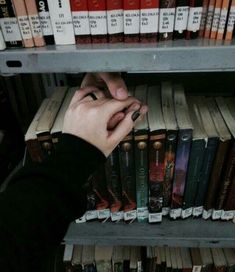 a person reaching for a book on a shelf in a library with bookshelves