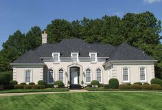 a large white house sitting on top of a lush green field